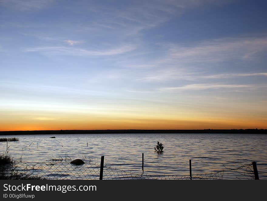 Lake sunset with a submerged chainlink fence in the foreground. Lake sunset with a submerged chainlink fence in the foreground