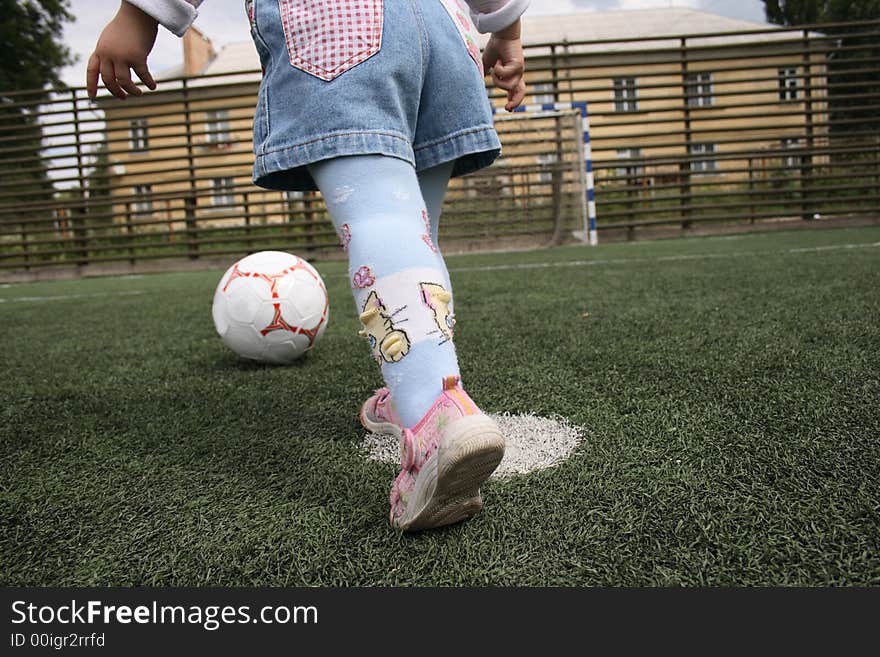 The child with a ball runs to a gate. The child with a ball runs to a gate