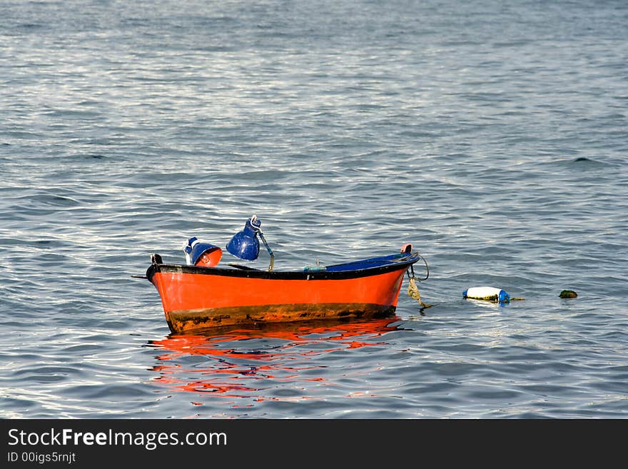 Small red painted fishing boat lies at anchor. Small red painted fishing boat lies at anchor