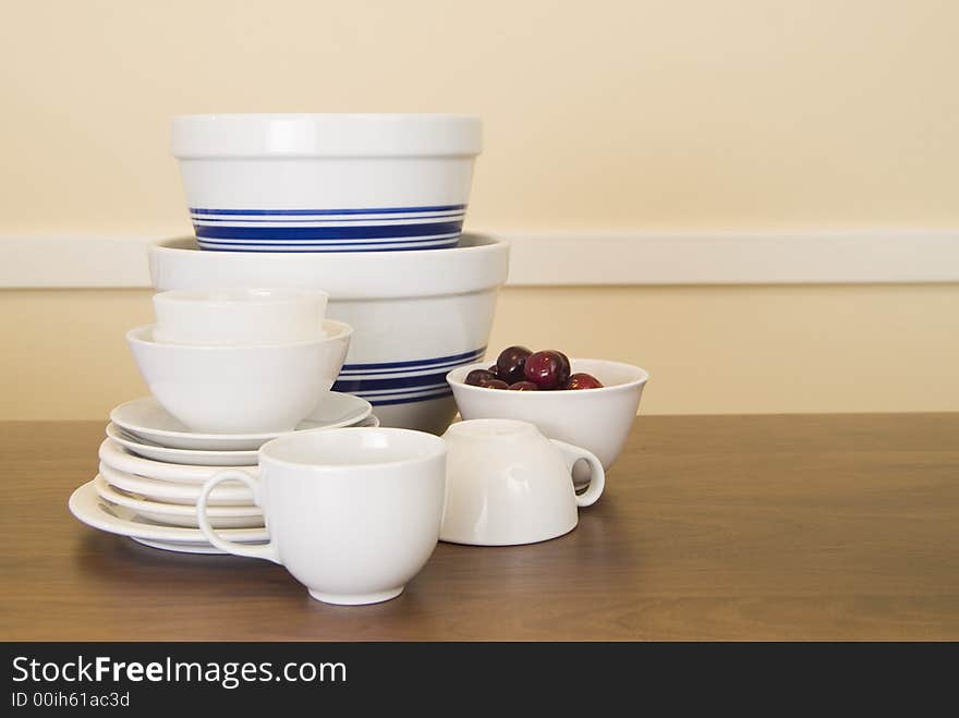 Group of dishes, cups, and bowls on dark wood table in a horizontal format. Group of dishes, cups, and bowls on dark wood table in a horizontal format.