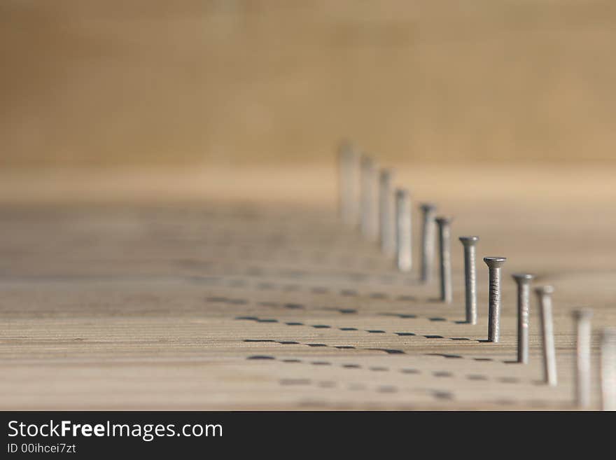 Line of nails in timber decking, only one nail in focus, very shallow depth of field.