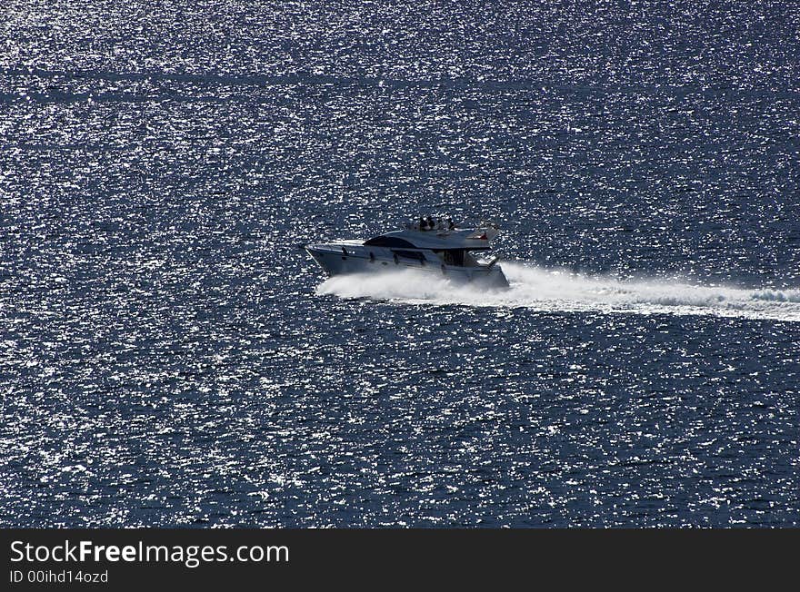 Small yacht speeds by silver surface of the sea. Small yacht speeds by silver surface of the sea