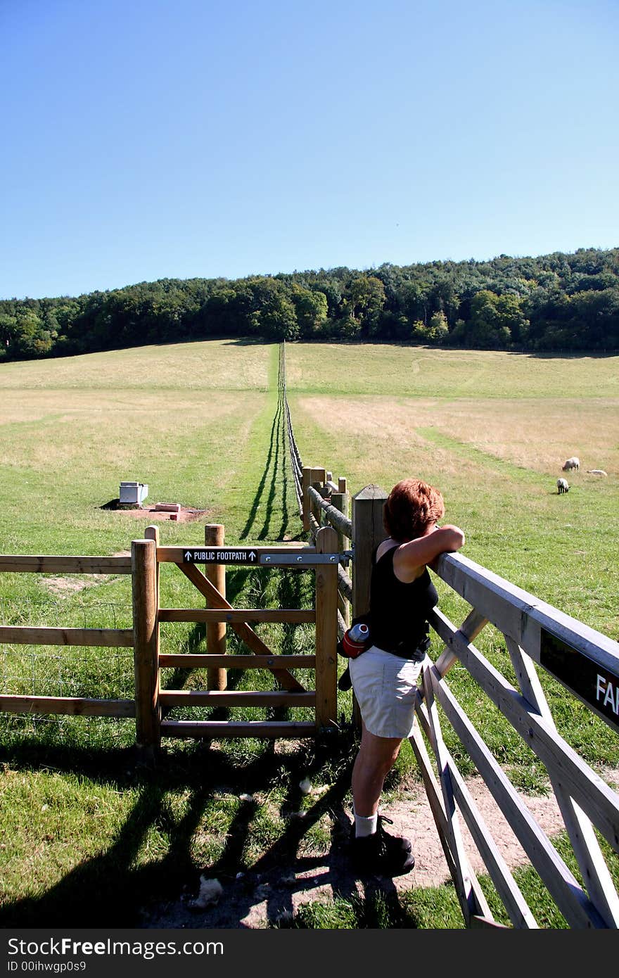 Lady Hiker on Rural English Footpath leaning on a gate and admiring the Scenery