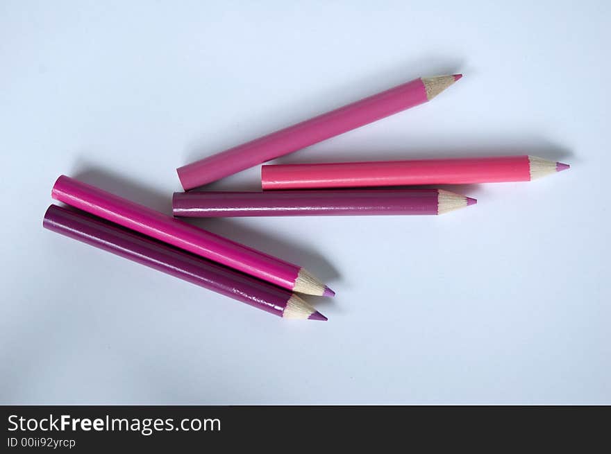 Pink and red colored pencils on white background.