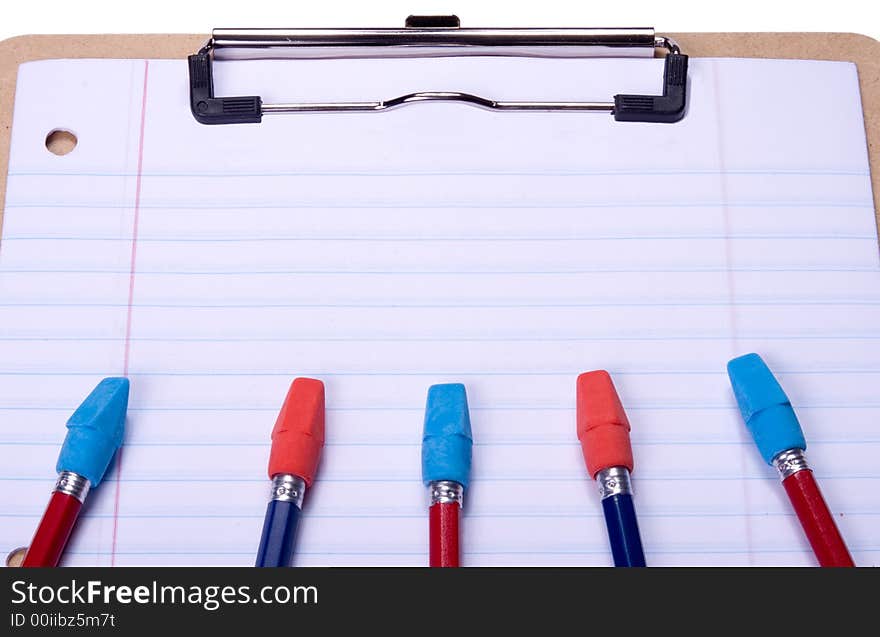 Clipboard with notebook paper, pencils and erasers arranged to provide copy space on paper. Clipboard with notebook paper, pencils and erasers arranged to provide copy space on paper.