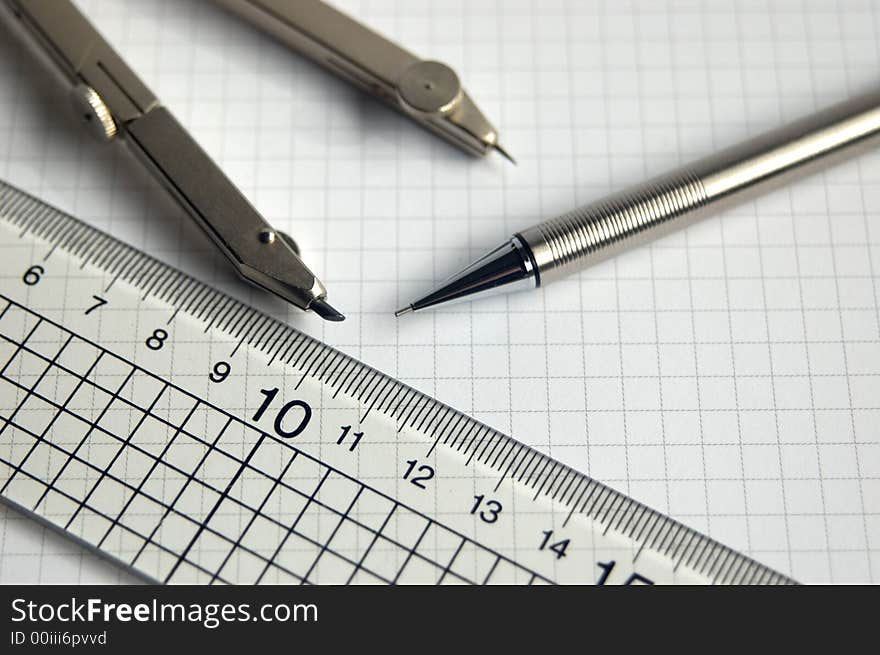 Pencil compass and ruler on white graph paper