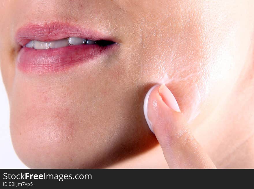 A young woman puts lotion on her face. A young woman puts lotion on her face.