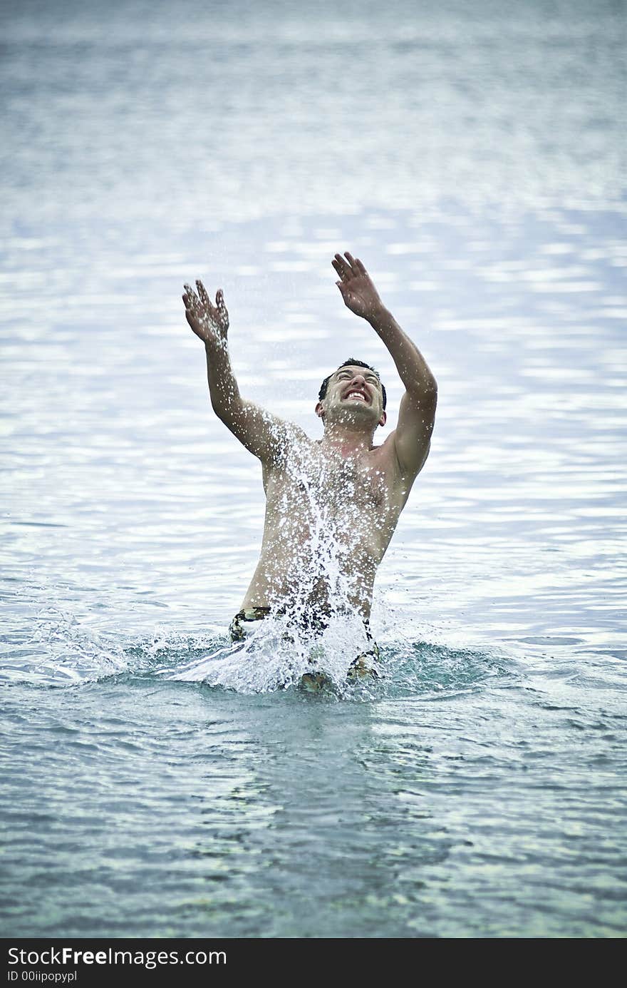 Young man jumping into sea water and preparing to swim