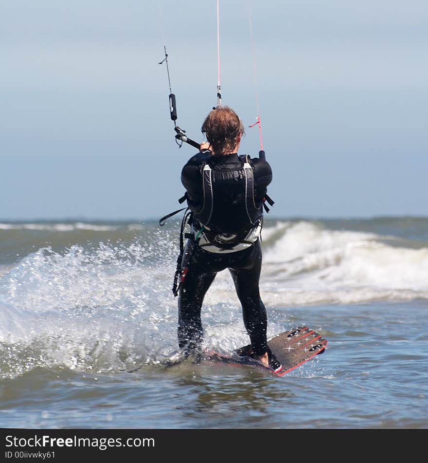 Action shot of a kite boarder at sea water hanging in the waves at high speed. Action shot of a kite boarder at sea water hanging in the waves at high speed.