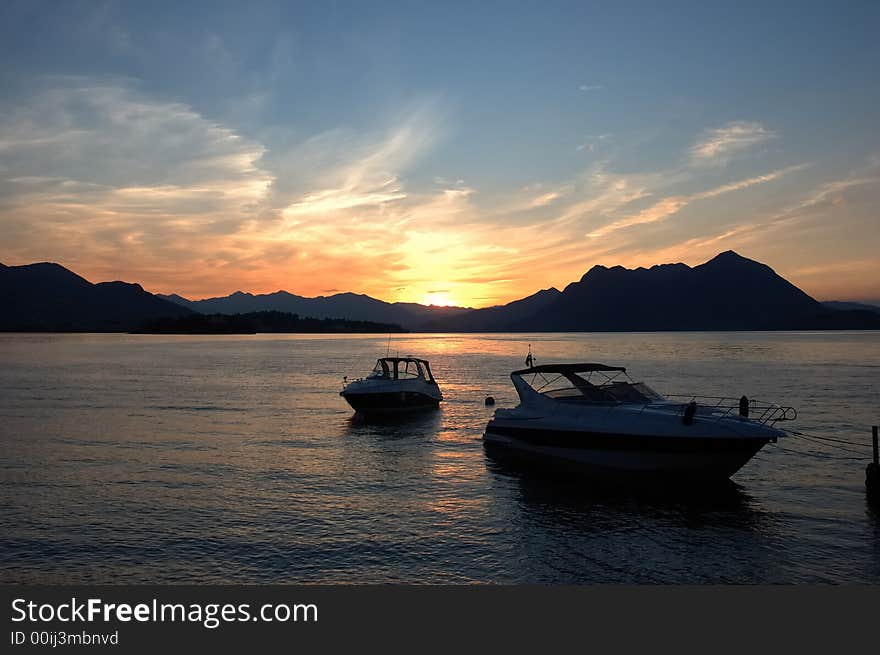 Small yachts anchored in quite lake water before the dawn; Maggiore Lake, Italy. Small yachts anchored in quite lake water before the dawn; Maggiore Lake, Italy.