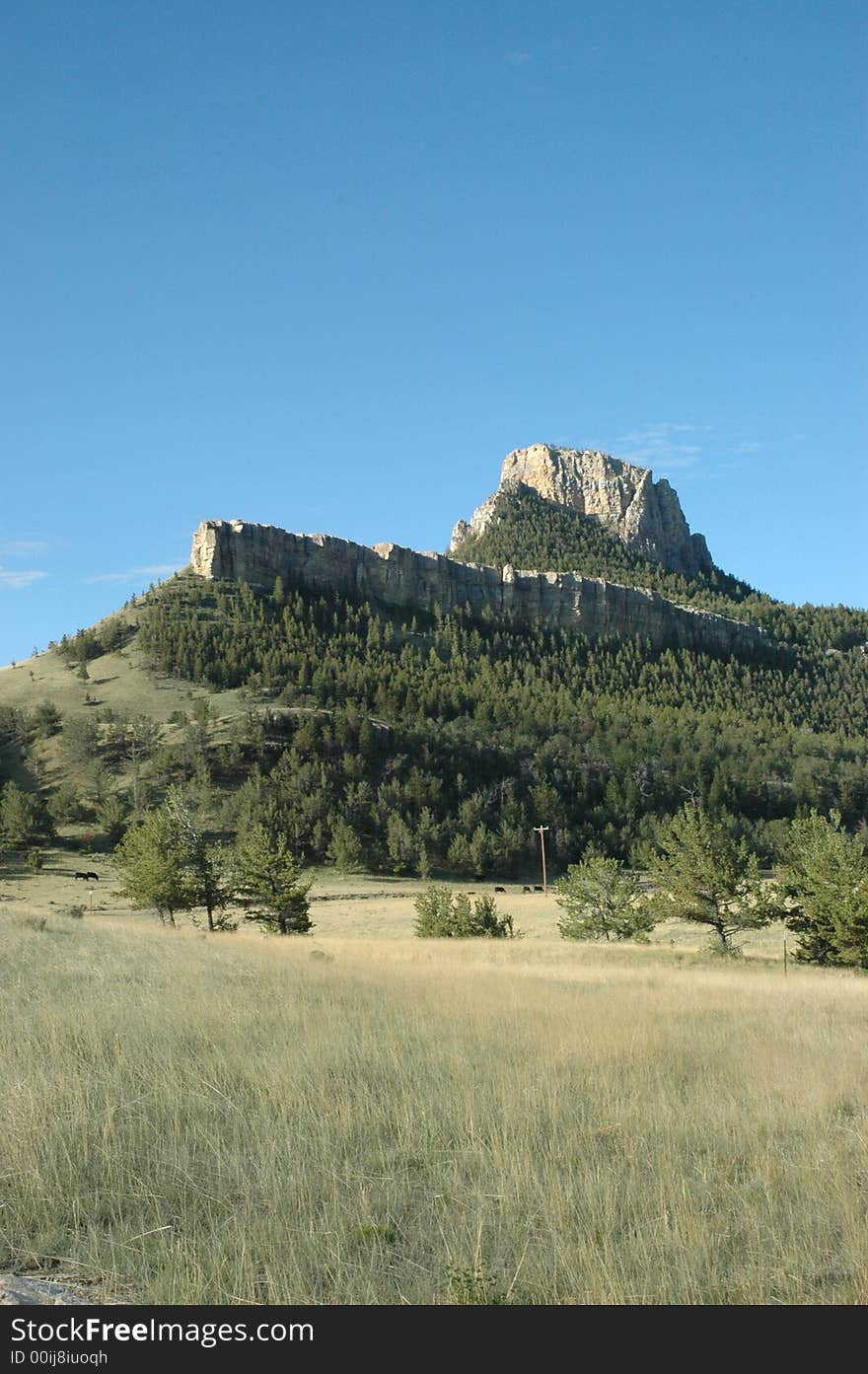 A small mountain peak view from across a grassland landscape. A small mountain peak view from across a grassland landscape.