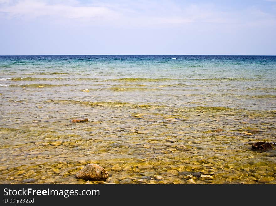 Landscape shot of lake huron on the beach bright blue colors rocks in the foreground. Landscape shot of lake huron on the beach bright blue colors rocks in the foreground