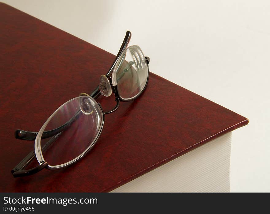 Book with pair of glasses on top. Book with pair of glasses on top