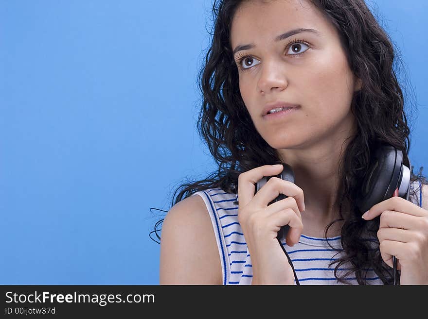 Young beautiful girl listening music on blue background