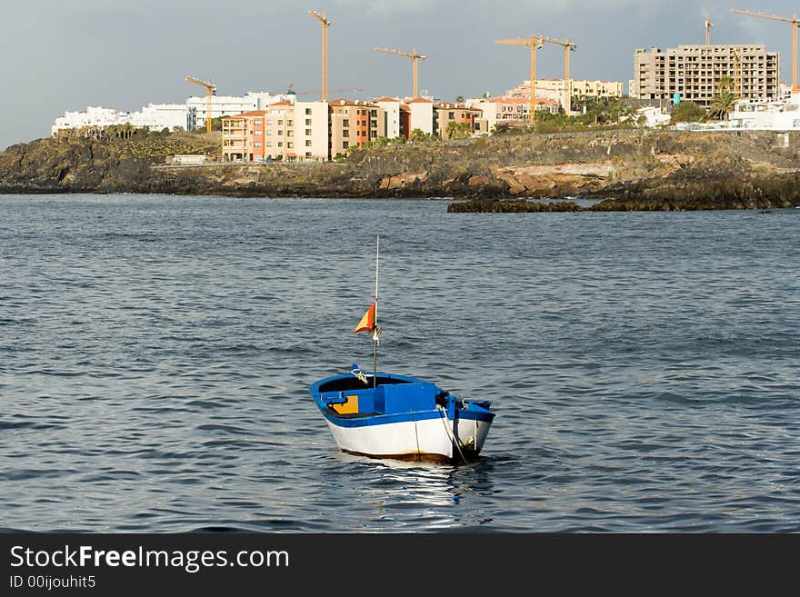 Small dinghy moored in front of new hotels being built. Small dinghy moored in front of new hotels being built