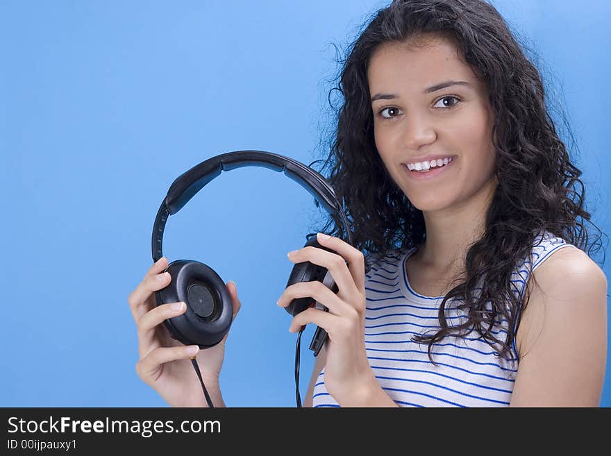 Young beautiful girl listening music on blue background