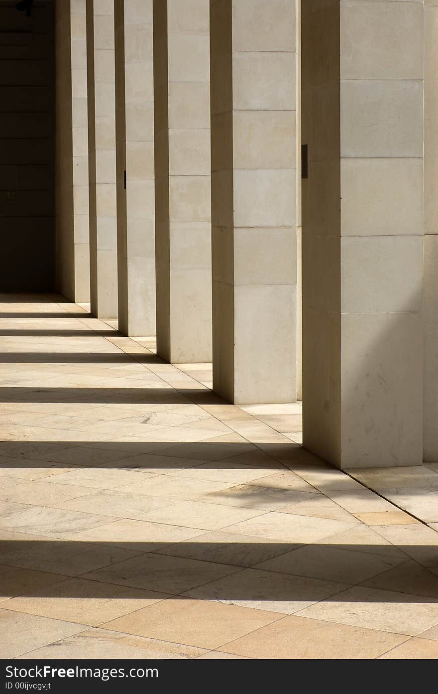 Stone columns lit from the side with long shadows cast upon the ground