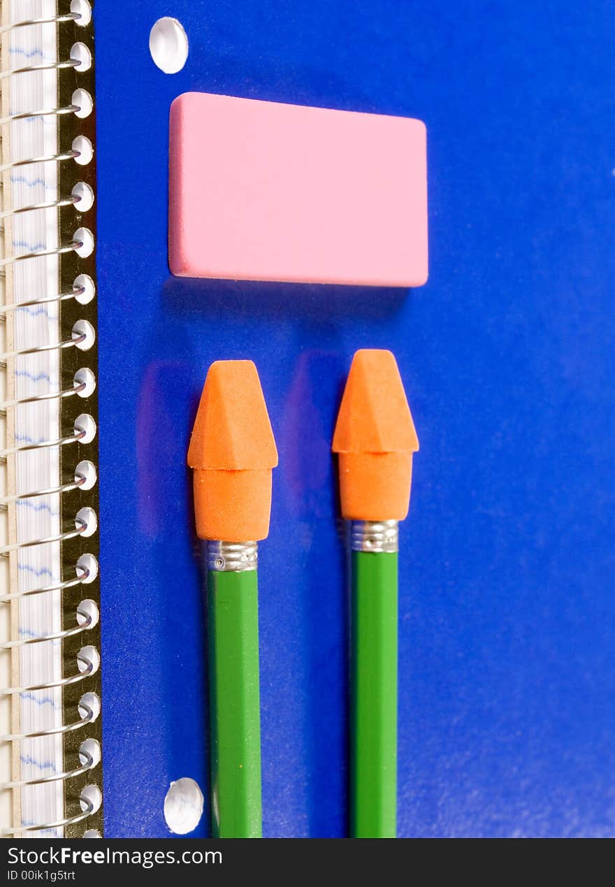 Blue spiral notebook with green pencils and pink eraser. Blue spiral notebook with green pencils and pink eraser