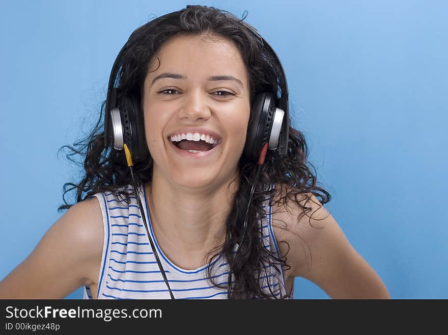 Young beautiful girl listening music on blue background