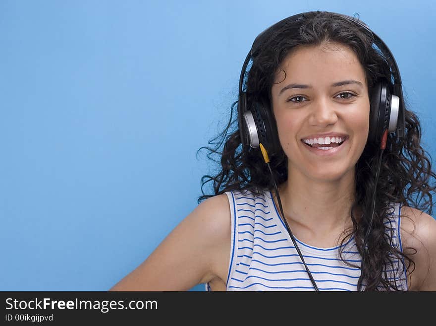 Young beautiful girl listening music on blue background