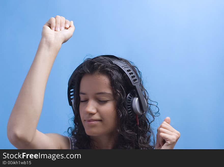 Young beautiful girl listening music on blue background