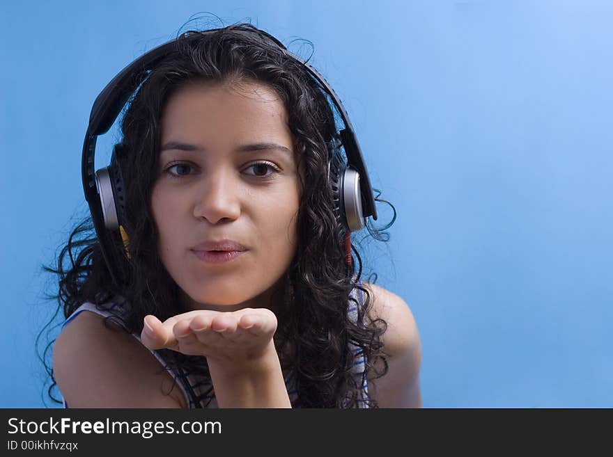 Young beautiful girl listening music on blue background