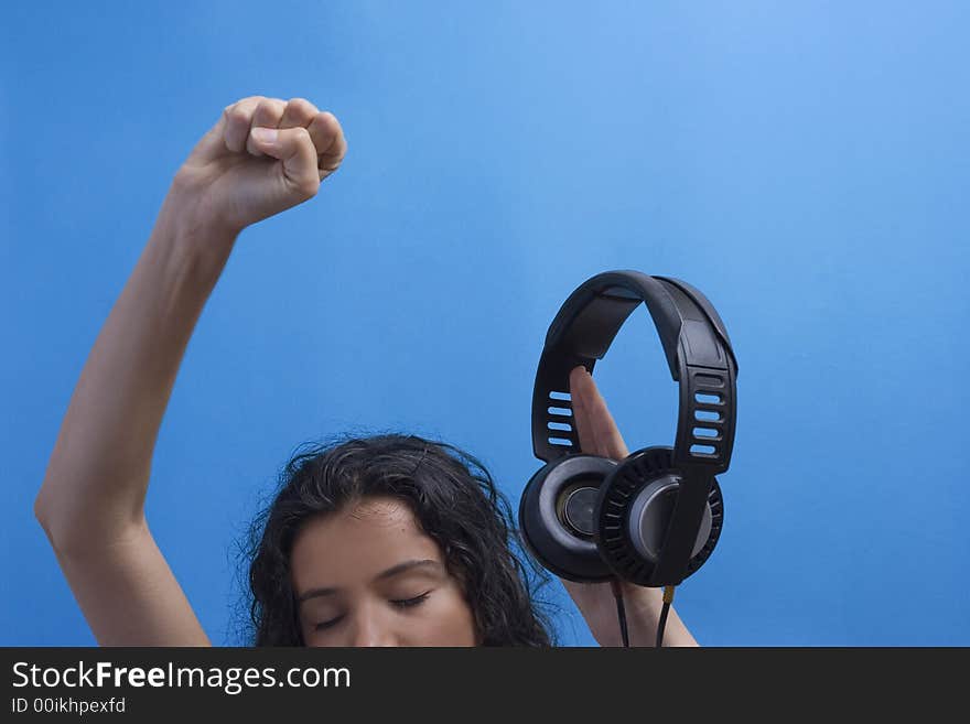 Young beautiful girl listening music on blue background