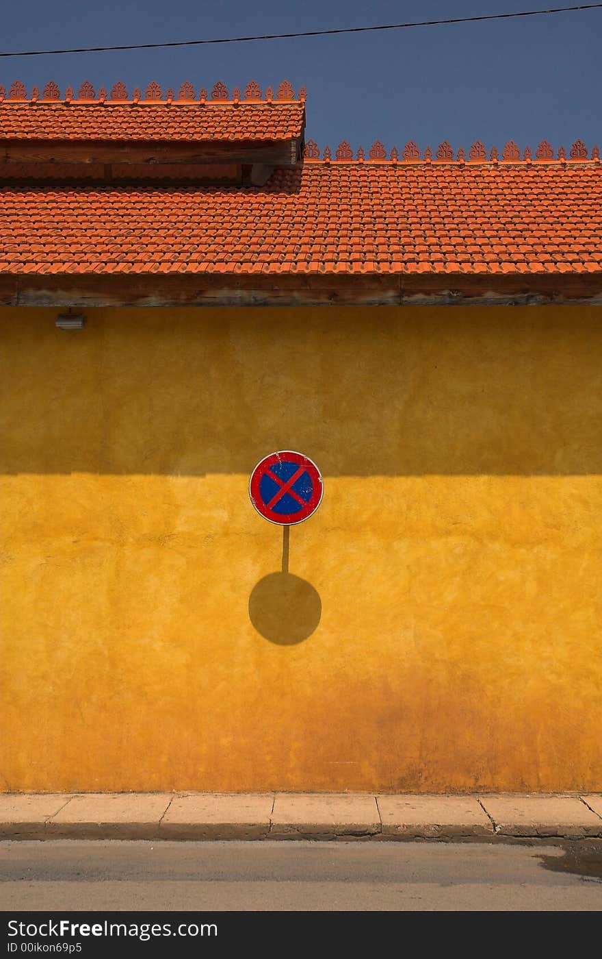 A no parking sign on an orange wall in the south of europe