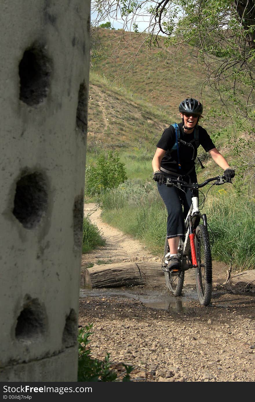 A woman mountain biker in the hills spashes through a puddle. A woman mountain biker in the hills spashes through a puddle