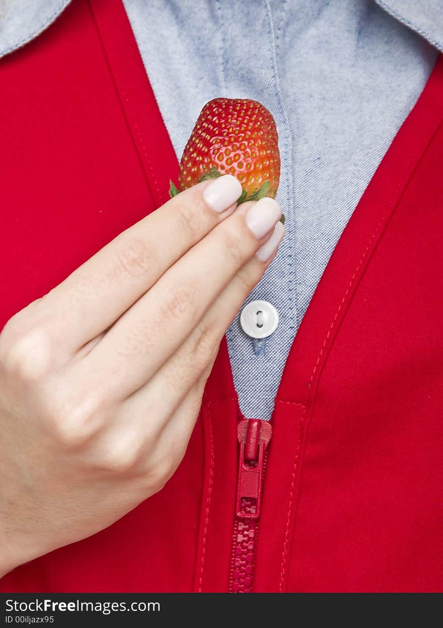 A fresh strawberry held by a female hand