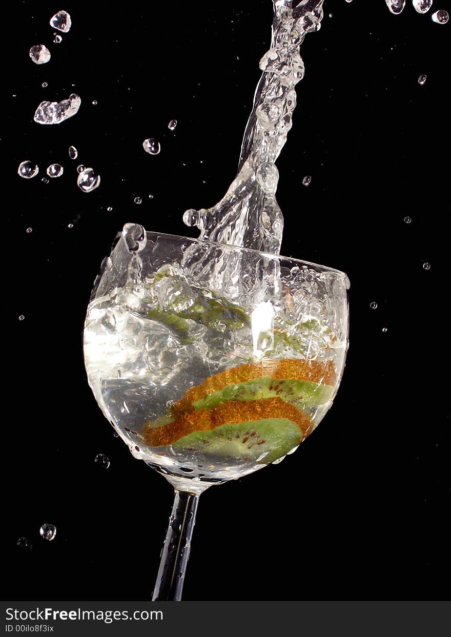 Kiwi fruit splashing into glass of water. Kiwi fruit splashing into glass of water