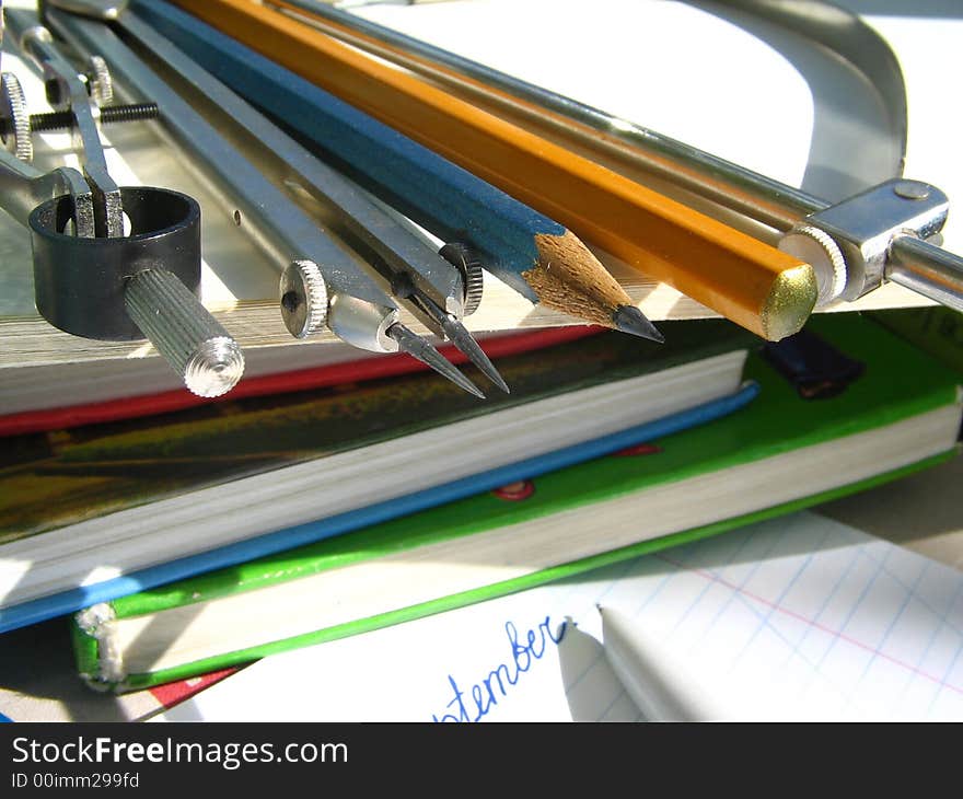 Pencils and compasses and pattern lay on a pile of books. Pencils and compasses and pattern lay on a pile of books.