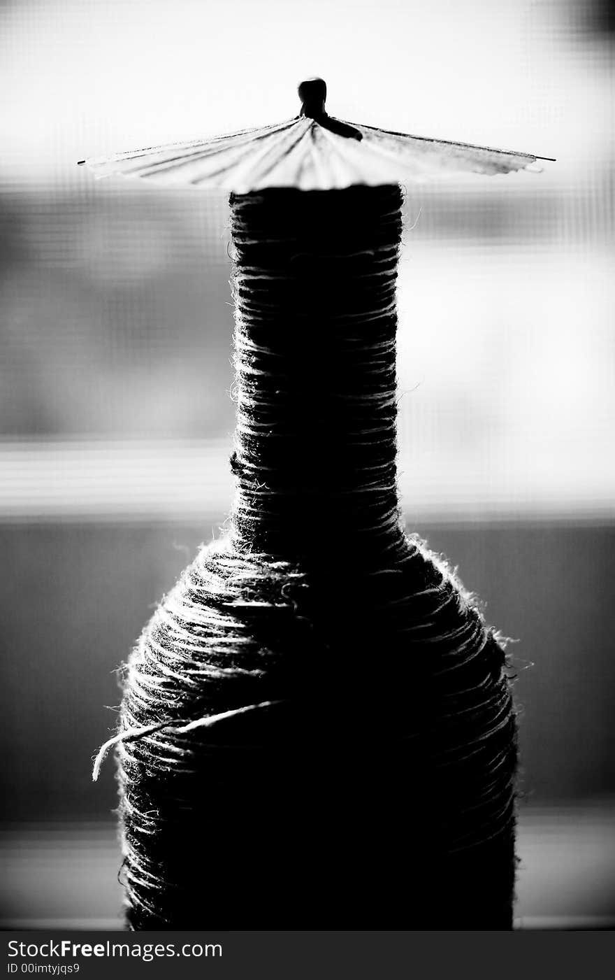 In abstract image in black and white, a bottle with an umbrella. In abstract image in black and white, a bottle with an umbrella