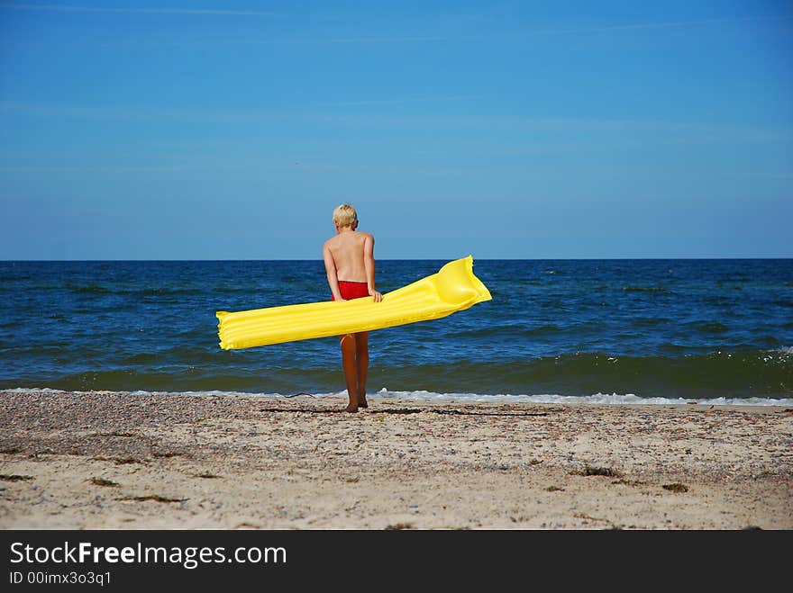 A boy with yellow airbed on the beach