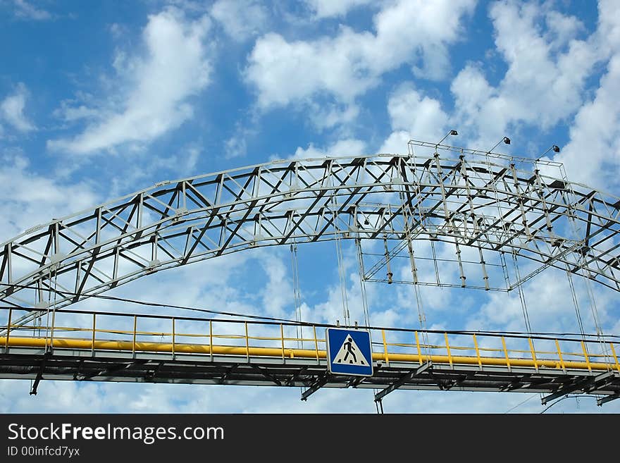 Pedestrian bridge crossing cloudy sky. Pedestrian bridge crossing cloudy sky