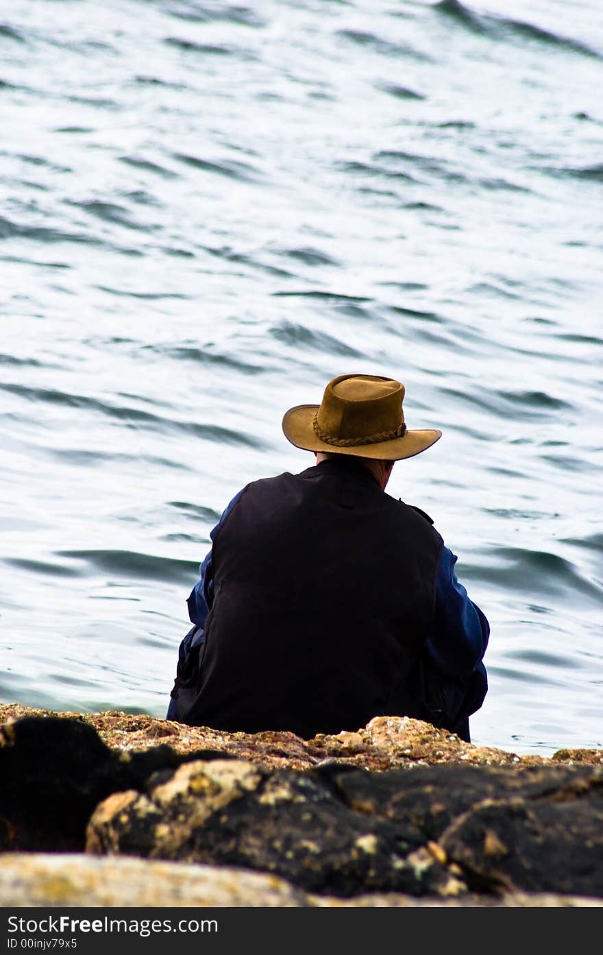 A man sitting thinking by the water's edge. A man sitting thinking by the water's edge.