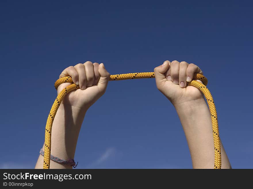 Two hands with an orange rope on sky background