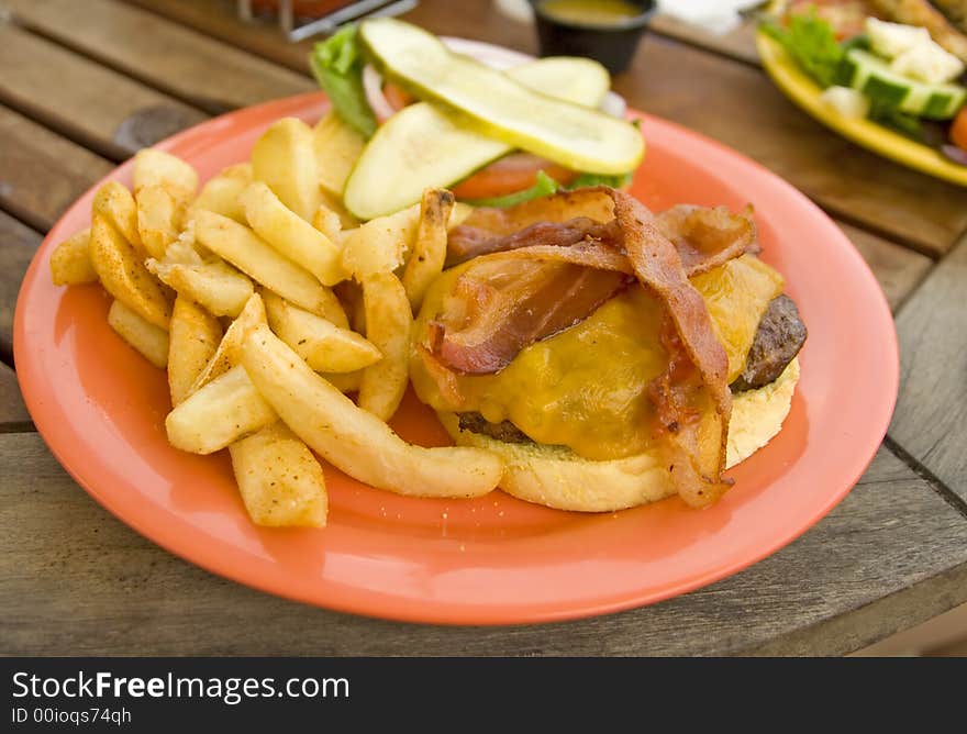 Delicious bacon burger served on a red plate. Delicious bacon burger served on a red plate