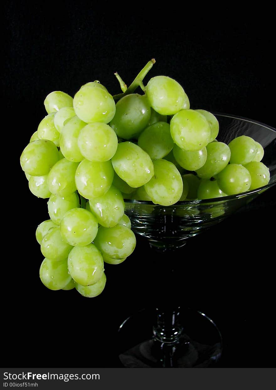 Cluster of green grapes falling out of a glass. Cluster of green grapes falling out of a glass