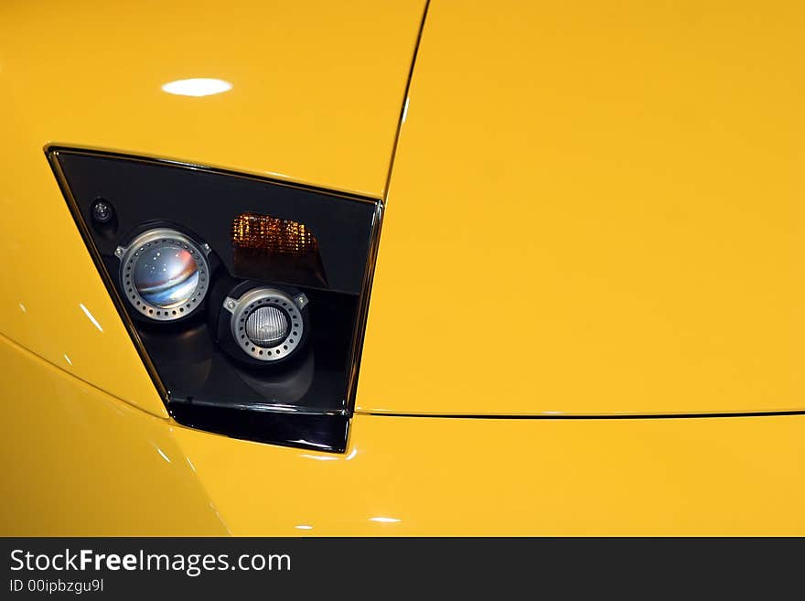 Yellow sportscar front reflector detail. Yellow sportscar front reflector detail