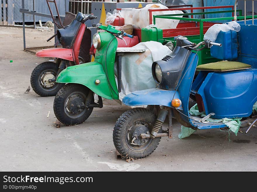 Three old transport scooters (super-light trucks) - blue, green and red (which is slightly out of depth of field). Three old transport scooters (super-light trucks) - blue, green and red (which is slightly out of depth of field)