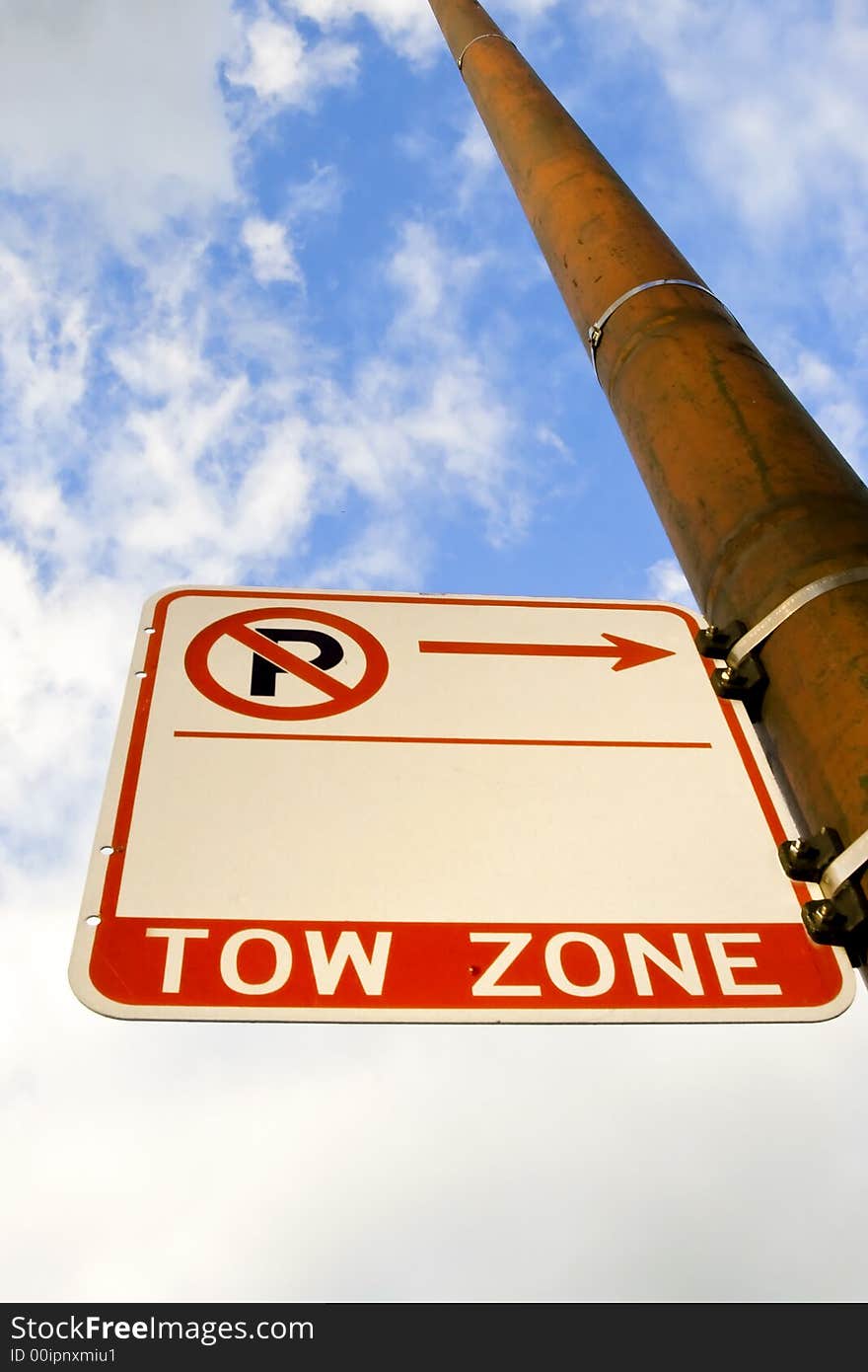 An upward angle of a Tow Zone sign on a pole with the sky in the background.