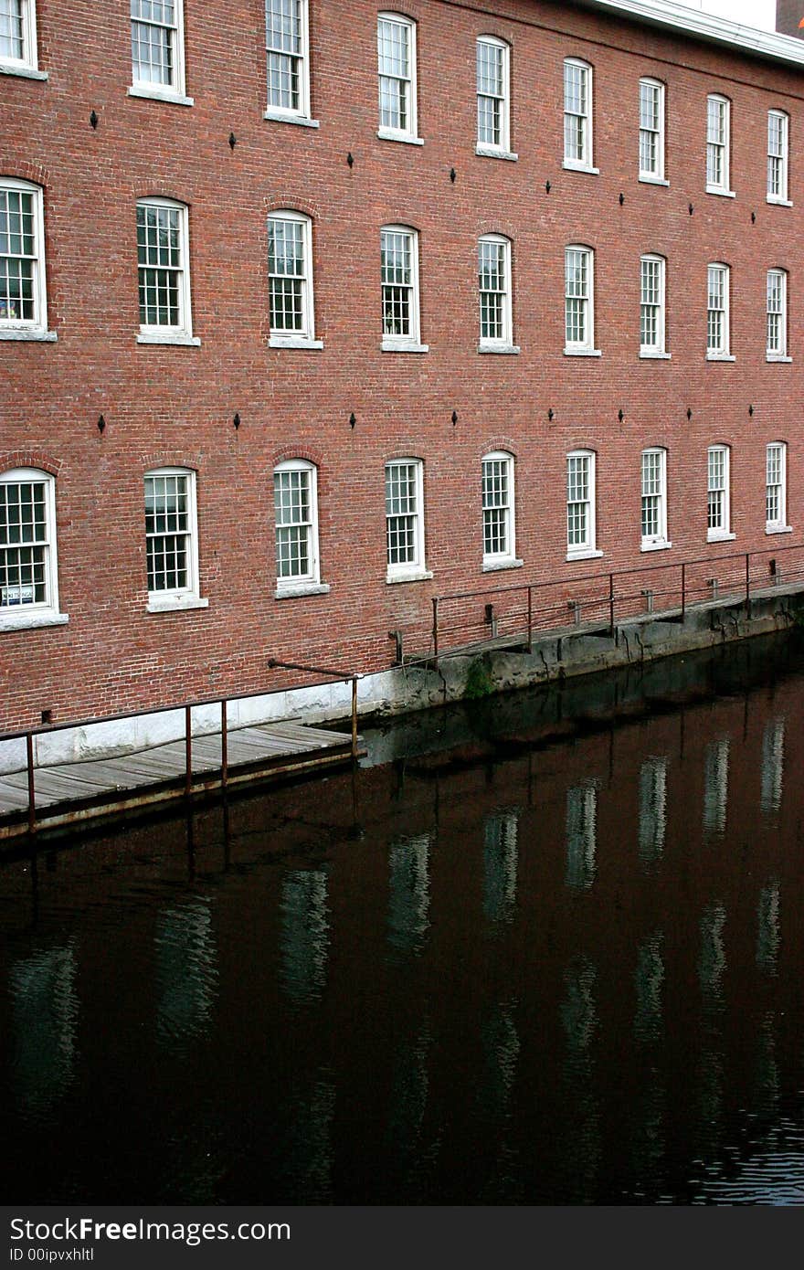 A river runs by historic Lowell, Massachusetts textile mill building. A river runs by historic Lowell, Massachusetts textile mill building