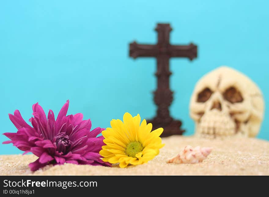 Flowers With Skull and Cross on Sand With Blue Background. Shallow DOF, Focus on Flowers. Flowers With Skull and Cross on Sand With Blue Background. Shallow DOF, Focus on Flowers