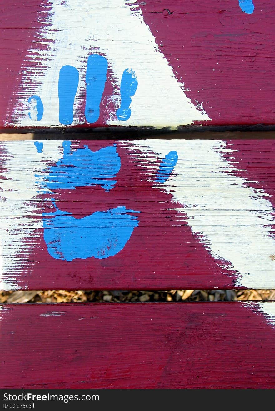 Blue painted hand on red painted picnic table, very fresh bright paint. Blue painted hand on red painted picnic table, very fresh bright paint.