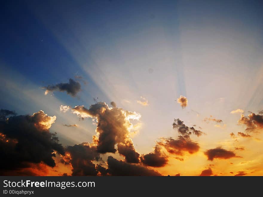 Sunset sky with clouds and light from the sun, blue and yellow-orange sky