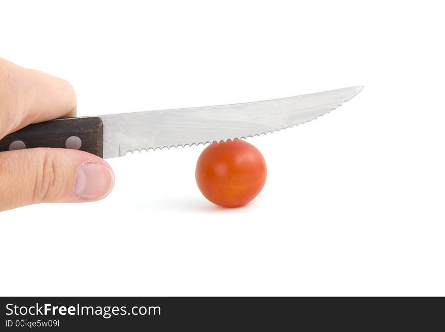 Photo of a knife in a hand cutting tomato