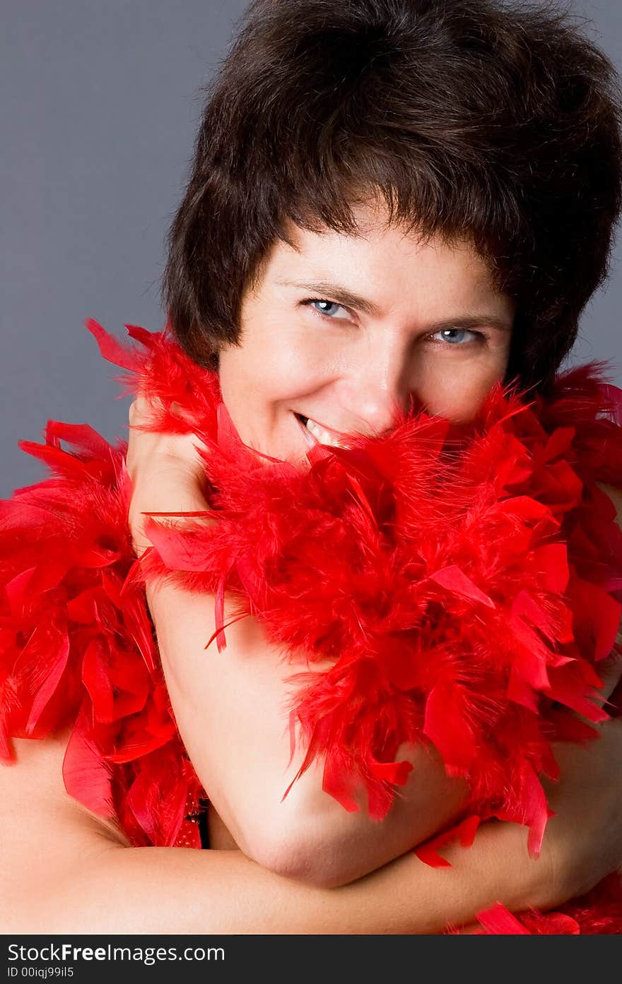 The attractive woman in a red boa, on a grey background. The attractive woman in a red boa, on a grey background