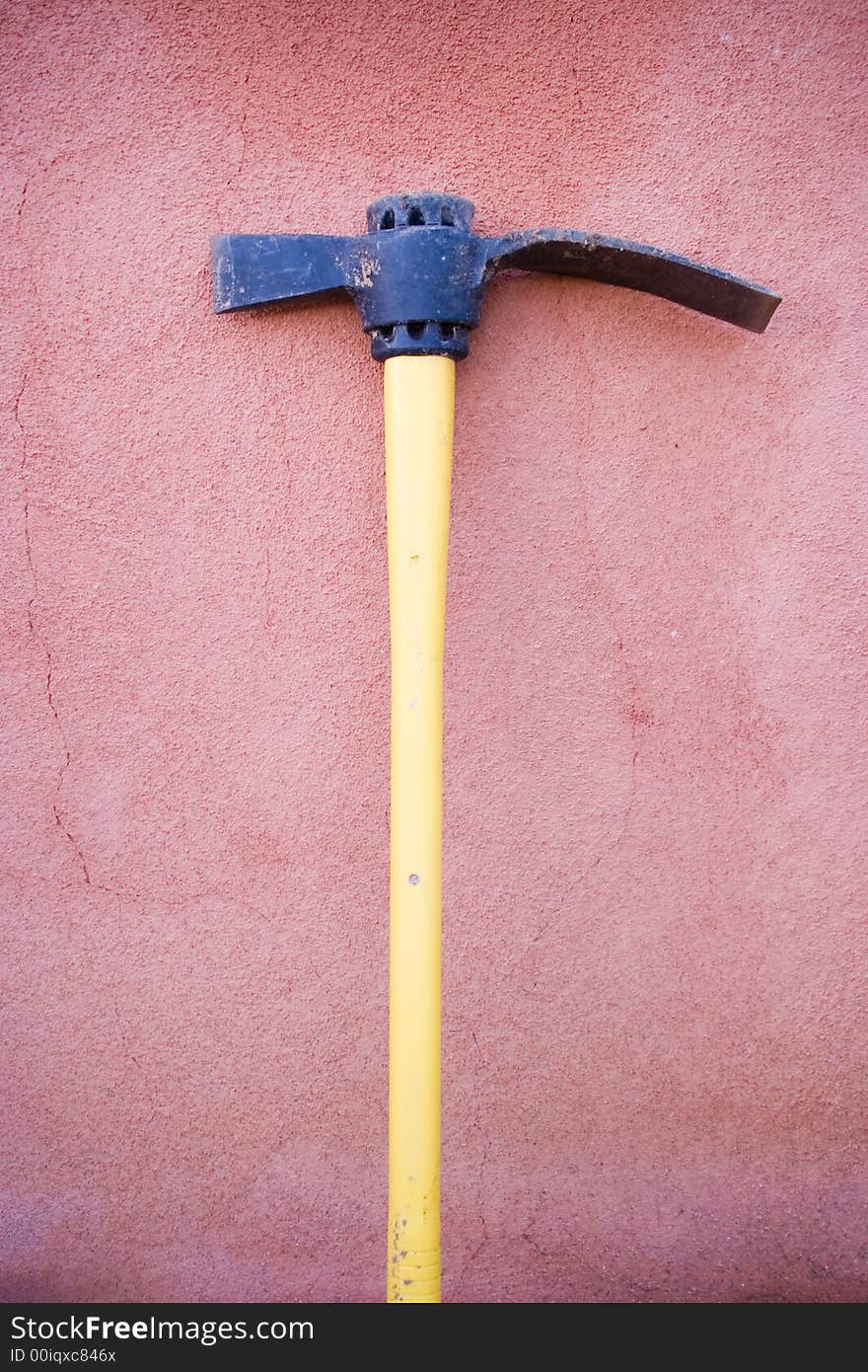 A yellow tool placed against a adobe wall. A yellow tool placed against a adobe wall