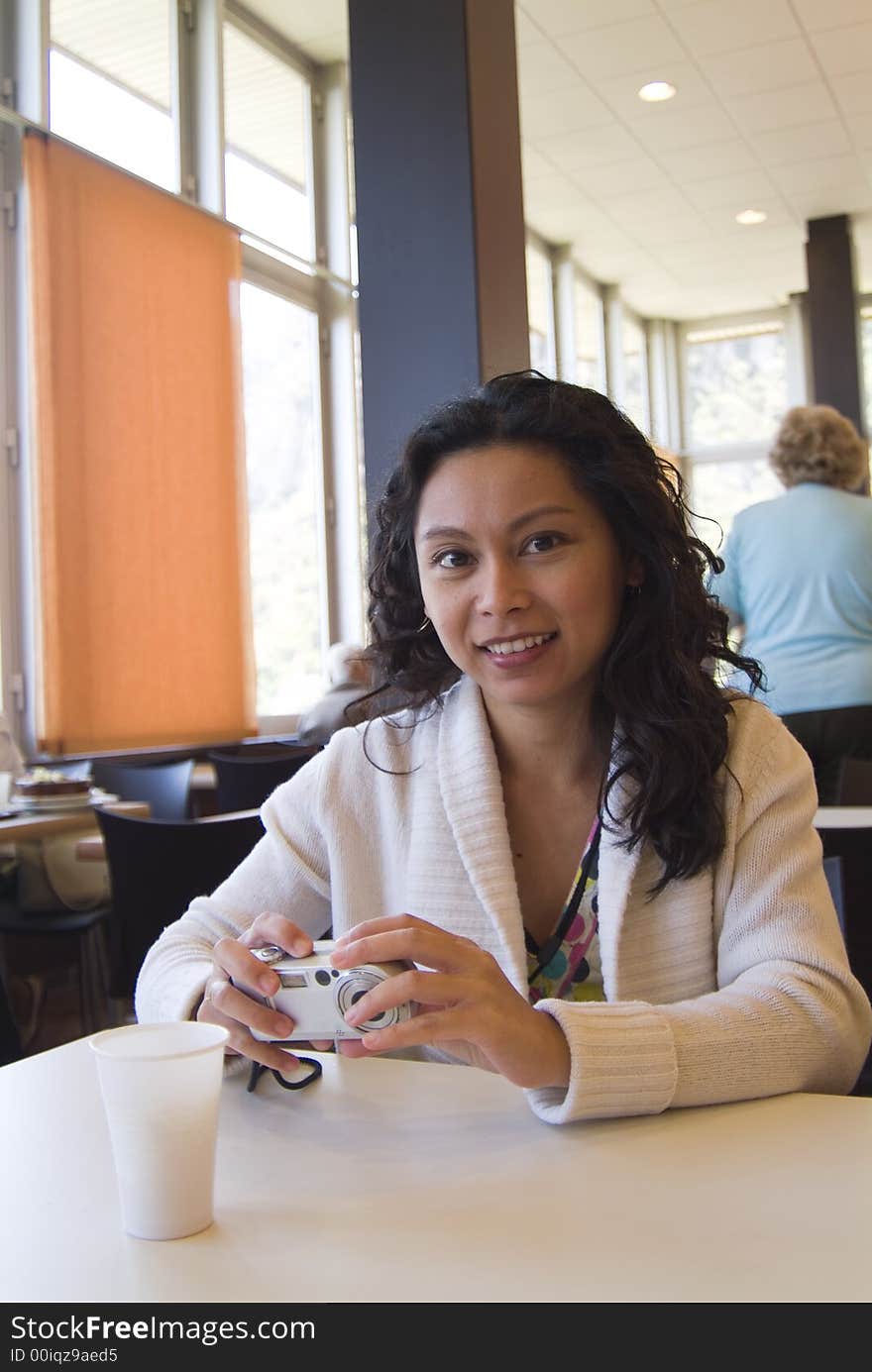 Asian woman with small camera sits at a lunch table at restuarant. Asian woman with small camera sits at a lunch table at restuarant.